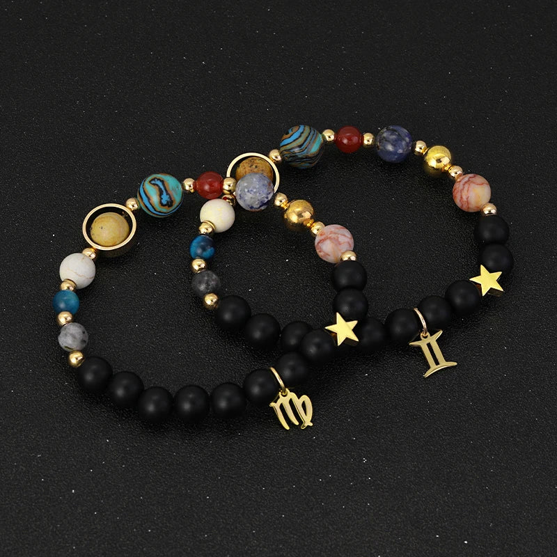 Set of three beaded bracelets with star, moon, and zodiac symbol charms on a black background